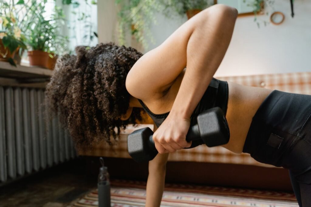 African American woman working out with dumbbells in an indoor setting, promoting a healthy lifestyle.